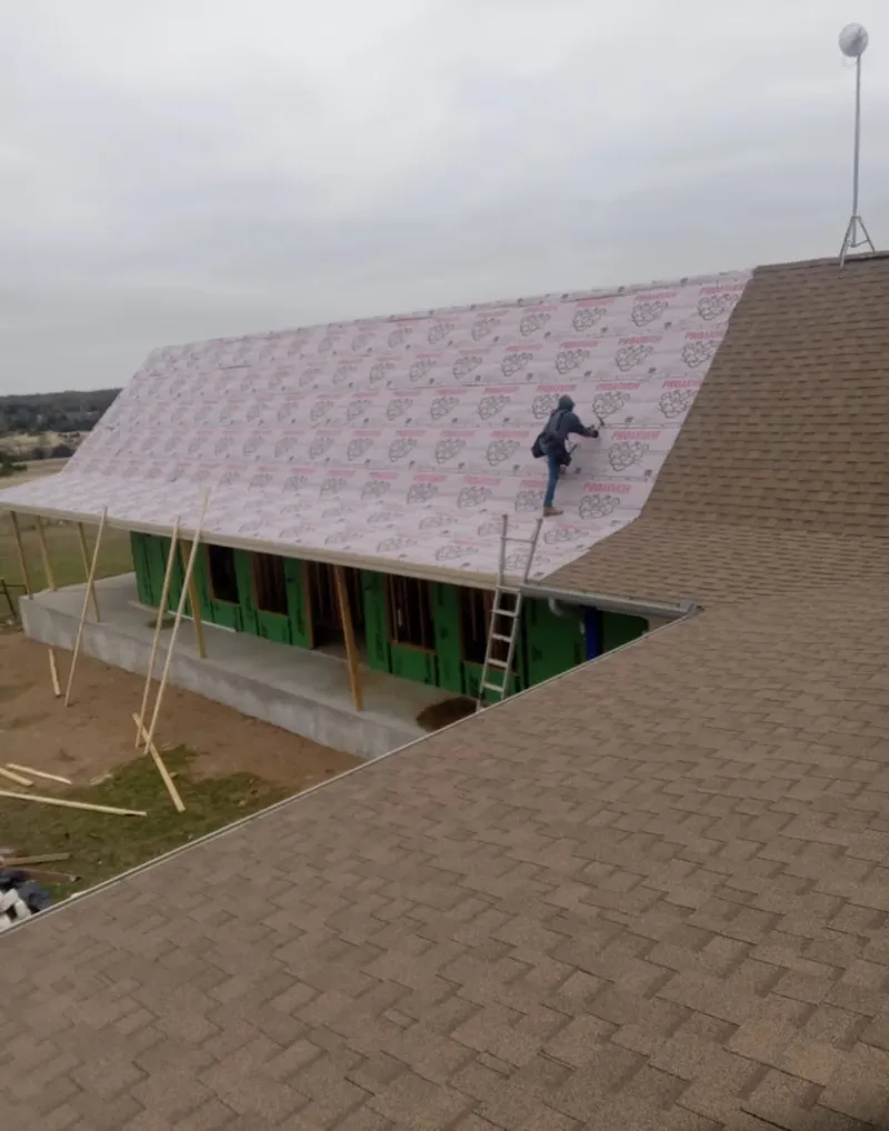 Worker preparing underlayment for a metal roof installation in Mendota Heights